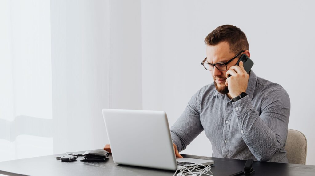 Agency recruiter checking candidate contact data on a phone at a desk