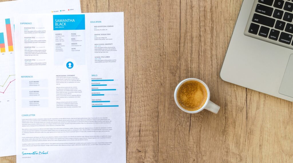 Recruiter reviewing a printed candidate CV and a branded summary page on a desk
