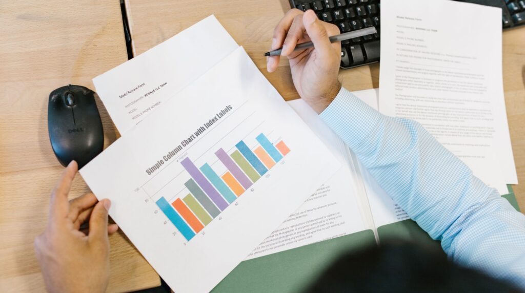 A recruitment consultant working at a desk with a spreadsheet open beside a CRM window
